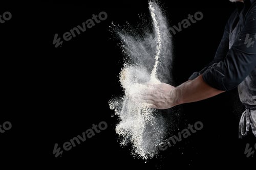 Preview: Chef in black uniform sprinkles white wheat flour in different directions