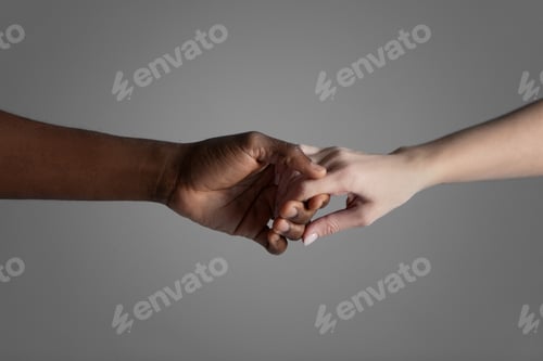 Preview: Hands of interracial couple on grey background.