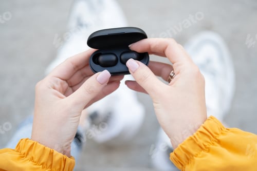 Preview: Female hands touching a portable gadget headphones.