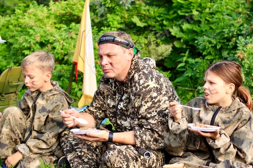 Preview: People in camouflage military uniform eating buckwheat porridge.