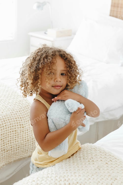 Preview: Child hugging a blue stuffed animal in a bright room.