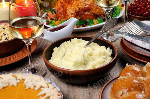 Preview: A bowl of mashed potatoes on a table among the pumpkin pie, baked turkey, cranberry-orange sauce,