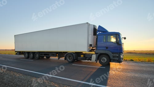 Preview: Semi-truck with cargo trailer driving on highway hauling goods in evening. Delivery transportation