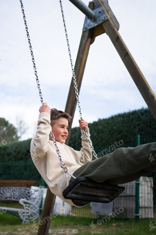 Preview: Happy child swinging on a swing in a playground