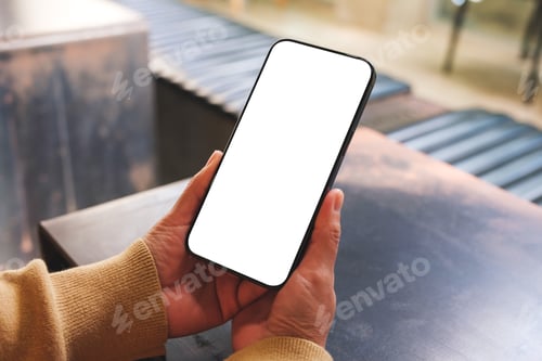 Preview: Mockup image of a woman holding and using mobile phone with blank desktop in cafe