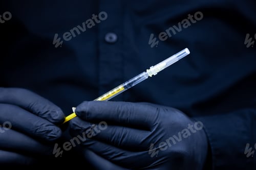 Preview: a doctor in black medical gloves holds a syringe for injection in front of him