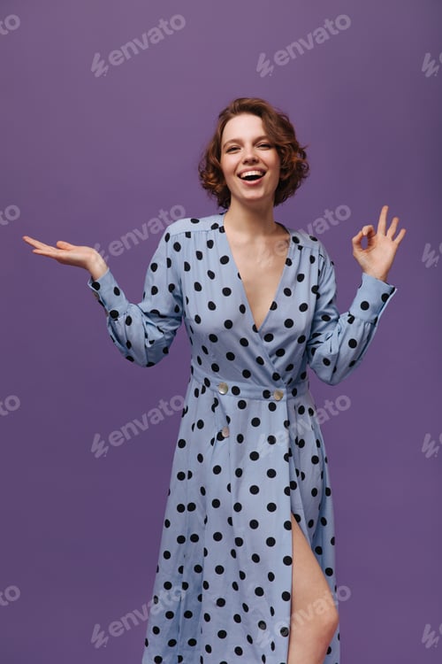 Preview: Portrait of joyful lady in blue dress against violet plain background. Young cheerful girl wearing