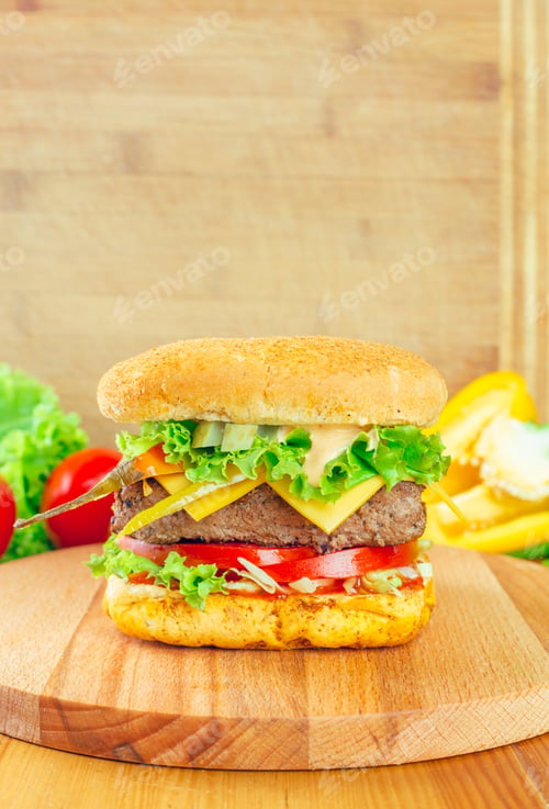 Preview: Delicious gourmet hamburger stacked high with fresh veggies and sauces on a wooden board