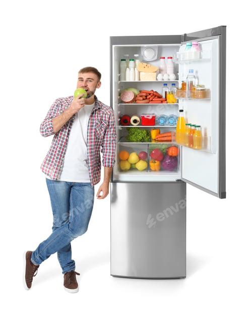 Preview: Young man eating apple near open refrigerator on white background