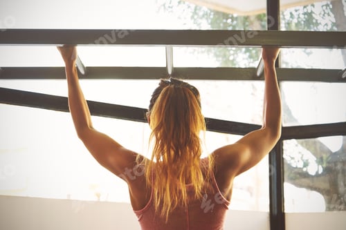Preview: Athlete fitness female model pulling up on horizontal bar in a g