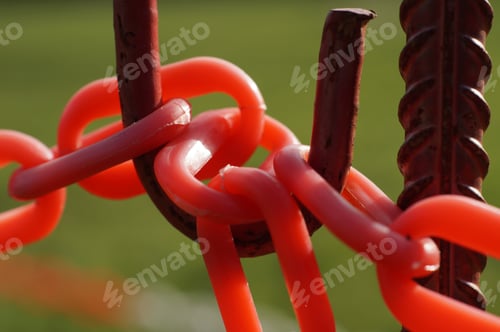 Preview: Closeup shot of red plastic barrier chains on rusted metal