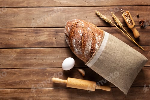 Preview: Loaf of fresh bread and bakery ingredients for homemade baking on wooden table