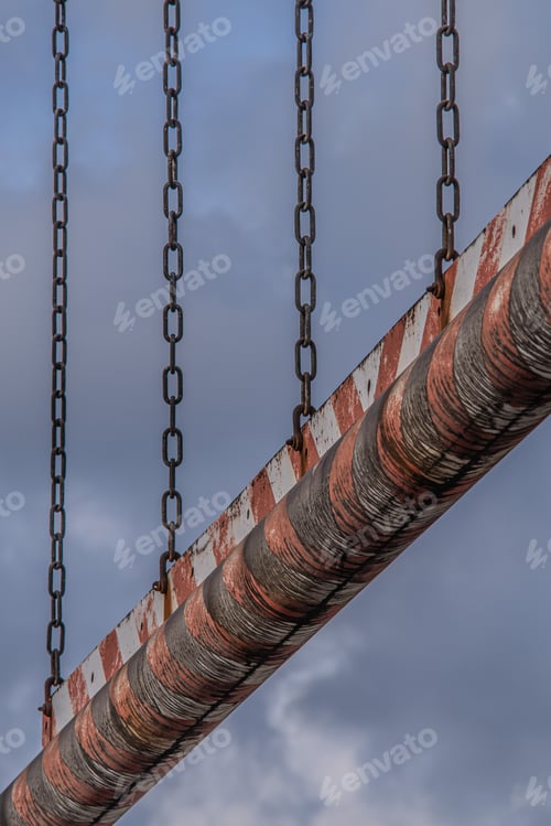 Preview: Old rusty pipe with chains against the blue sky