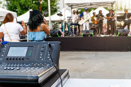 Preview: Close up of soundboard with the band playing concert on the stage