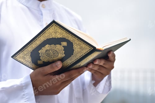 Preview: Holy Quran in hand with arabic calligraphy meaning of Al Quran.