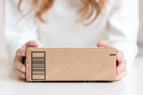 Preview: Woman holding in hands delivered goods in cardboard box. Mock-up friendly design with copy space.