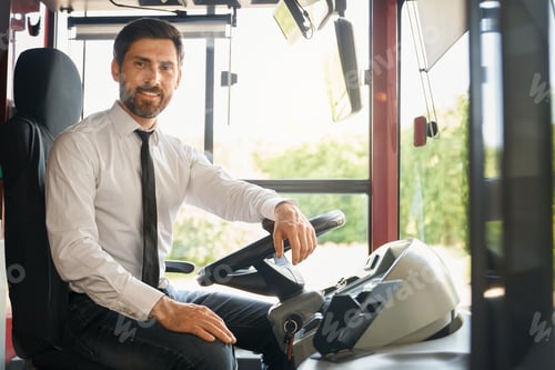 Preview: Elegant driver posing to camera, while sitting behind bus steering wheel.