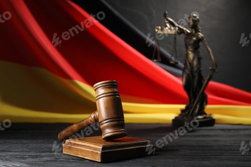 Preview: Judge's gavel, flag of Germany and statue of Lady Justice on black wooden table, closeup
