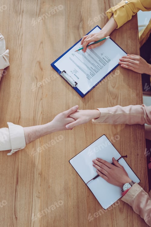 Preview: top view of woman shaking hands with recruiter near coworker with clipboard and pencil