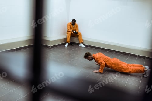Preview: prisoner doing push-ups on floor in prison cell
