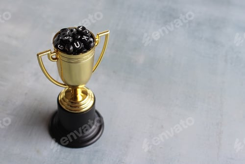 Preview: Alphabet beads inside gold trophy cup with copy space