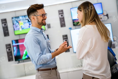 Preview: Happy seller man helping to woman to buy a new digital smart device in tech store