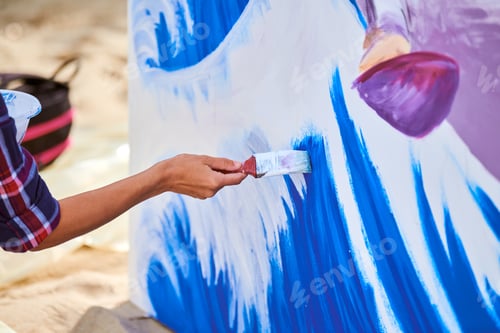 Preview: Female artist working on abstract acrylic painting, hand holding paint brush, large canvas outdoor