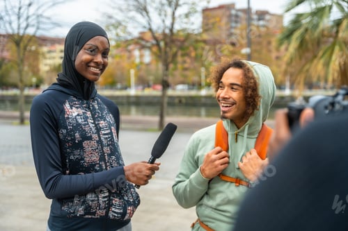 Preview: Diverse reporter interviewing smiling man in urban setting outdoors