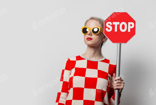 Preview: Beautiful woman with blond hair in in a 70s red square dress with stop sign