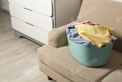Preview: Laundry basket with dirty clothes on sofa indoors. Space for text