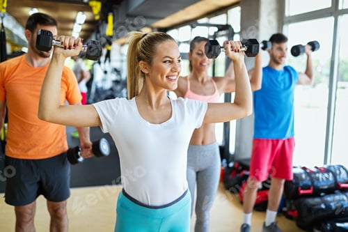 Preview: Group of young fit people doing exercises in gym to stay healthy