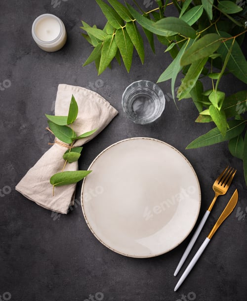 Preview: Table setting with a beige plate, a glass, a candle and a napkin with eucalyptus branches
