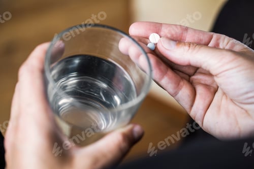 Preview: Man holding glass of water and pills
