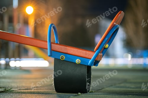 Preview: Seesaw swing in preschool yard with soft rubber flooring at night.