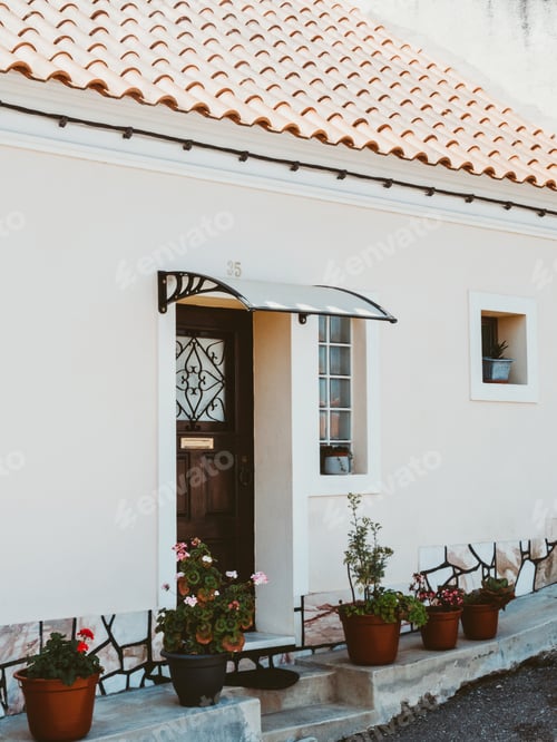 Preview: Traditional white stone house with tiled roof and various flowers pot