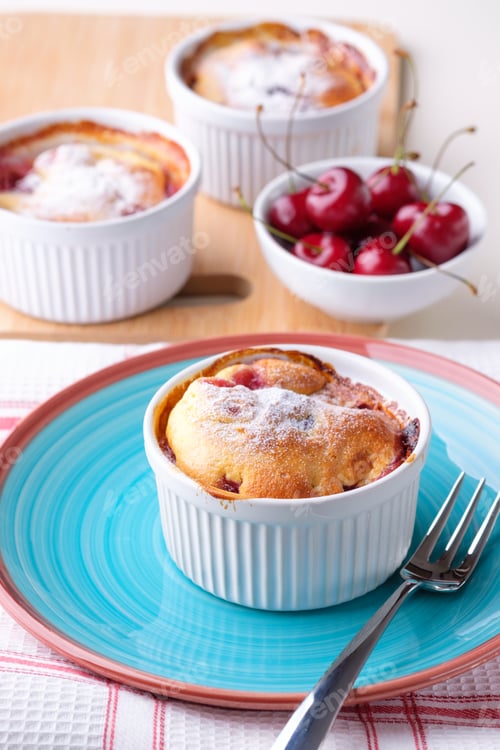 Preview: Traditional french baked cherry pie clafoutis served in white ramekin. Vertical.