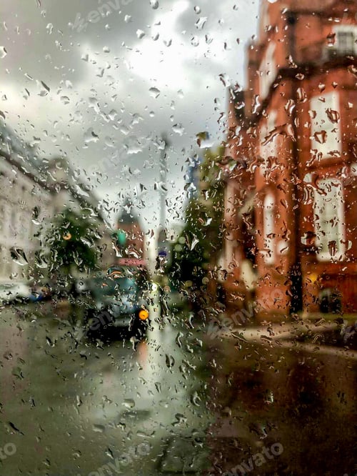 Preview: Street view of London through the window covered raindrops.Blured houses and traditional british cab