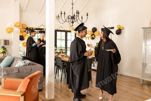 Visualização: Graduates in caps and gowns celebrating with friends at home, enjoying conversation