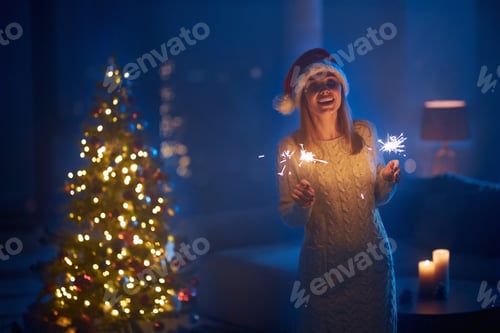 Preview: Woman standing near christmas tree with sparklers in hands