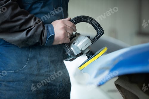 Preview: A man who sanding with a grinder and prepares the paint for the car in a car service.