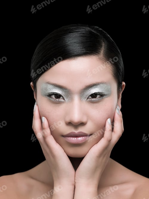 Preview: Elegant woman with striking eye makeup touches her face