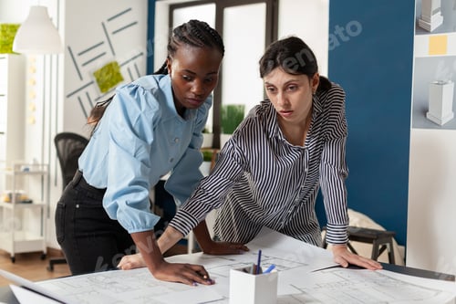 Preview: Comitted team of engineers partners discussing construction plans standing at desk
