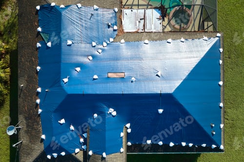 Preview: Top view of leaking house roof covered with protective tarp sheets against rain water