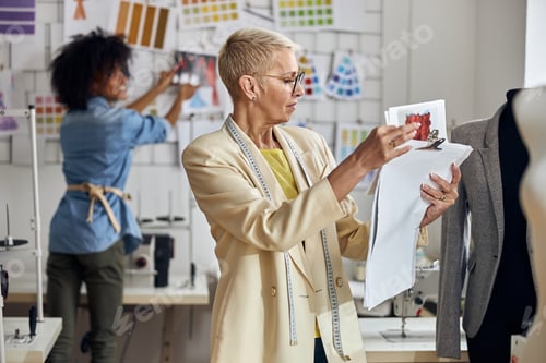 Preview: Middle aged lady looks at drawings while African-American stagist puts picture on wall