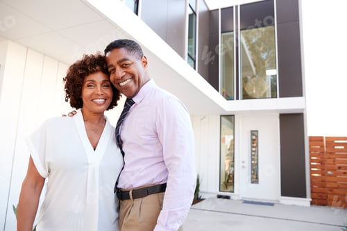 Preview: Middle aged black couple stand outside admiring their modern home, back view