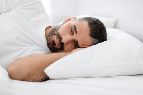Preview: Sleepy Bearded European Man Lying In Bed Awake At Home