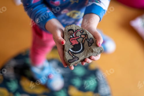 Preview: Young girl showing her amazing artwork painting on a rock of a dancing figure