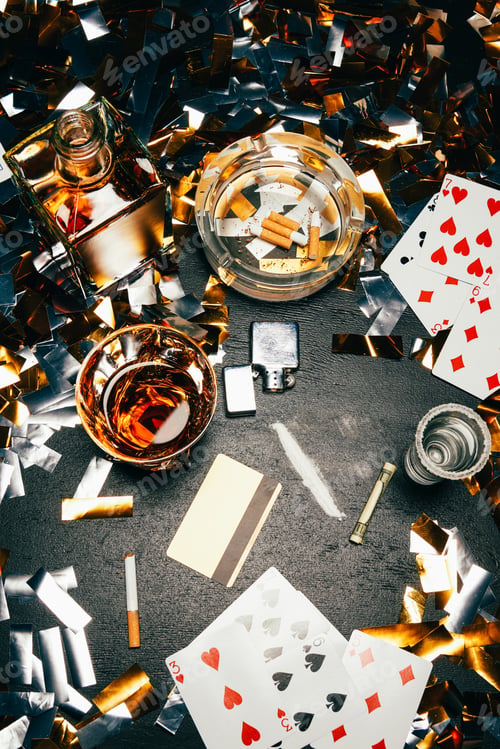 Preview: view from above of playing cards, cigarettes, whiskey, rolled banknote, credit card and cocaine on
