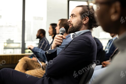 Preview: Seated male entrepreneur engaging in questions with microphone