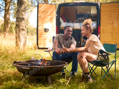 Preview: Couple Camping In Countryside With RV Toasting Marshmallows Outdoors On Fire